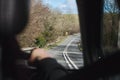 Rear passenger point of view from interior of car travelling, looking out the window on a country road