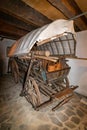 Rear photo of a traditional cart with wooden wheels, covered with material and loaded with various wooden objects