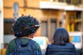 Rear portrait of two woman walking at Murcia city. One of them with afro hair and exotic decoration and ornament on her