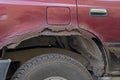 Rear right wing and bottom of door with threshold of a serviceable maroon car covered with traces of metal corrosion and rust Royalty Free Stock Photo