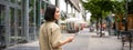 Rear shot of young woman walking in city, going down the street and smiling, holding smartphone. View from behind Royalty Free Stock Photo