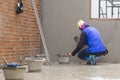 Rear side view of Asian builder using trowel to polishing concrete wall in house construction site