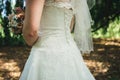 Rear side view on bride in white wedding dress holding wedding bouquet. Woman in park. Wedding day concept. Royalty Free Stock Photo