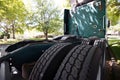 Rear tires tread of a green big rig semi truck parked on a street under the trees