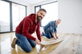 A mature man with his senior father laying vinyl flooring, a new home concept.