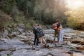 Rear on two couples standing and hugging at river on rocks. Hikers in mountains valley. Royalty Free Stock Photo