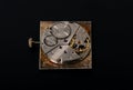 Rear viev of golden old pocket watch with open clockwork lying on black table surface. Mechanism of golden vintage watch