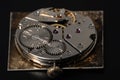 Rear viev of golden old pocket watch with open clockwork lying on black table surface. Mechanism of golden vintage watch