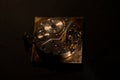 Rear viev of golden old pocket watch with open clockwork lying on black table surface. Mechanism of golden vintage watch