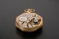 Rear viev of golden old pocket watch with open clockwork lying on a gray surface. Mechanism of golden vintage watch with