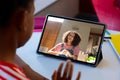 Rear view of a african american boy having a video call with female teacher on a tablet at home Royalty Free Stock Photo