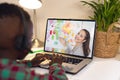 Rear view of a african american boy using laptop having a video call with biracial female teacher Royalty Free Stock Photo