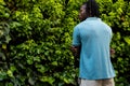 Rear view of african american man with dreadlocks wearing pale blue polo shirt in garden, copy space Royalty Free Stock Photo