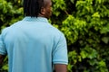 Rear view of african american man with dreadlocks wearing pale blue polo shirt in garden, copy space Royalty Free Stock Photo