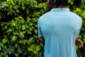 Rear view of african american man with dreadlocks wearing pale blue polo shirt in garden, copy space Royalty Free Stock Photo