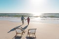 Rear view of african american senior couple holding hands and walking towards sea under sky Royalty Free Stock Photo