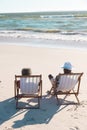 Rear view of african american senior couple looking at seascape and relaxing on deckchairs at beach Royalty Free Stock Photo