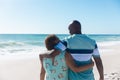 Rear view of african american senior couple standing with arms around at beach with copy space Royalty Free Stock Photo