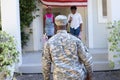 Rear view of african american soldier father greeting son and daughter in front of house