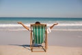 Woman With Arms Stretched Out Sitting On Beach Chair At Beach In The Sunshine