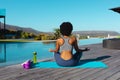 Rear view of african american woman practicing yoga and meditating near the pool Royalty Free Stock Photo