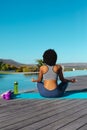 Rear view of african american woman practicing yoga and meditating near the pool Royalty Free Stock Photo