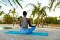 Rear view african american woman practicing yoga meditation sitting on beach deck, copy space Royalty Free Stock Photo