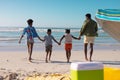 Rear view of african american young parents holding children\'s hands running at beach against sky Royalty Free Stock Photo