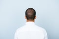 Rear view of an american muklatto guy, in smart white formal shirt, standing on a pure blue background. Snap model shot. Hair car