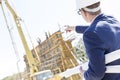 Rear view of architect holding blueprints while pointing at construction site Royalty Free Stock Photo