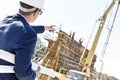 Rear view of architect holding blueprints while pointing at construction site Royalty Free Stock Photo