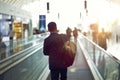 Rear view of Asian businessman walking on airport escalator at sunset