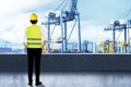 Rear view of an Asian construction worker with hardhat looking at the seaport Royalty Free Stock Photo