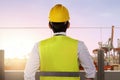 Rear view of an Asian construction worker with hardhat looking at the seaport