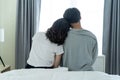 Rear view of Asian couple sitting together after wakeup in the morning. Attractive new marriage man and woman in pajamas feel