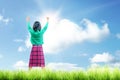 Rear view of asian cute girl standing while raised arms on the grass field Royalty Free Stock Photo