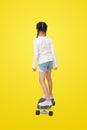 Rear view Asian little girl child riding on skateboard isolated on yellow background. Image with clipping path Royalty Free Stock Photo