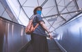 Asian plus size female passenger in protective mask looking back at camera while going up on escalator at subway station Royalty Free Stock Photo