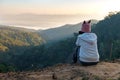 Rear view of asian woman sitting on the ground looking on the view of beautiful nature on the top of mountain. Royalty Free Stock Photo