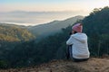 Rear view of asian woman sitting on the ground looking on the view of beautiful nature on the top of mountain. Royalty Free Stock Photo