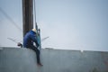 Rear view of an Asian worker working on the edge of a building at the construction site Royalty Free Stock Photo