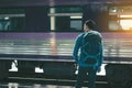 Rear view of asian young hipster man standing and waiting train Royalty Free Stock Photo