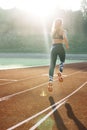 Rear view of athletic woman running on track stadium at summer morning light. Fit woman running on racetrack during Royalty Free Stock Photo