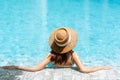 Rear view of attractive Asian woman in bikini and straw hat relaxing in luxury swimming pool Royalty Free Stock Photo