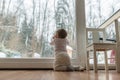 Rear view of baby girl kneeling by the dirty glass door