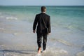 Rear view of back business man in suit in sea water at beach. Handsome business man on summer vacation. Businessman Royalty Free Stock Photo