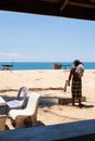 Bare-chested asian senior fisherman stands on the beach