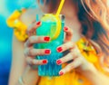 Rear view of beautiful woman is holding orange juice glass at poolside in summer closeup. Royalty Free Stock Photo