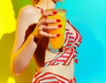 Rear view of beautiful woman is holding orange juice glass at poolside in summer closeup. Royalty Free Stock Photo