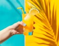 Rear view of beautiful woman is holding orange juice glass at poolside in summer closeup. Royalty Free Stock Photo